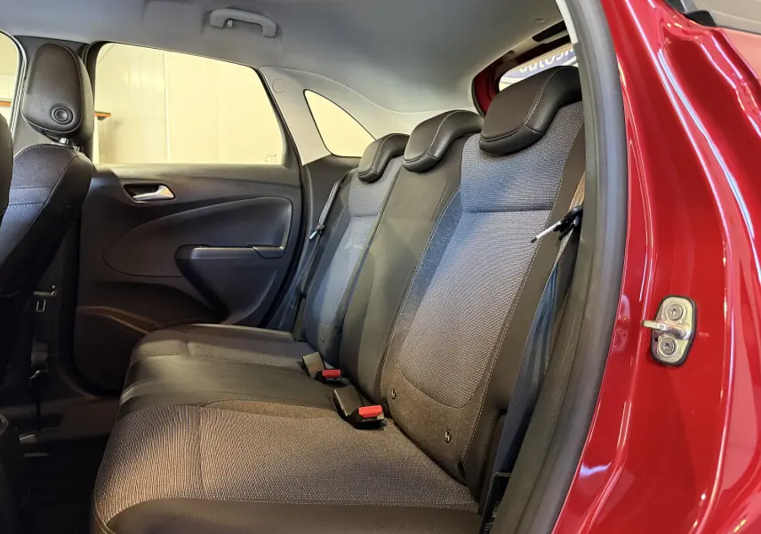 Vue intérieure côté droit des sièges arrière en tissu gris et noir de l’Opel Crossland rouge 2022 avec porte ouverte.