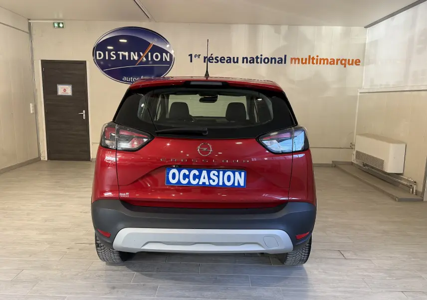 Vue arrière d'un Opel Crossland rouge 2022 avec plaque "OCCASION" dans un showroom lumineux.