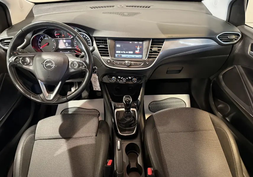 Vue intérieure frontale de l’Opel Crossland 2022, tableau de bord noir avec volant multifonction et boîte manuelle.