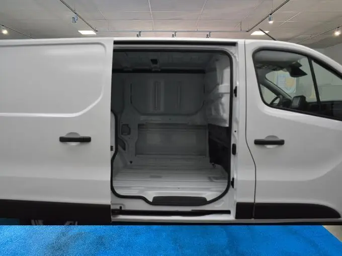 Vue latérale droite d’un Renault Trafic Fourgon blanc L1H1 avec porte coulissante ouverte montrant l’espace de chargement vide.