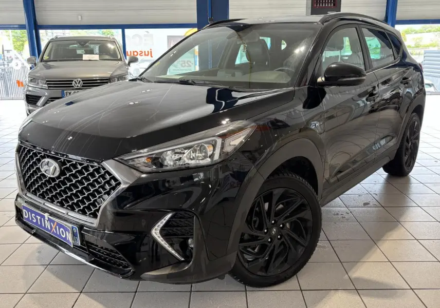 Hyundai Tucson noir en 3/4 avant droit, avec calandre N Line chromée et jantes alliage noires 19 pouces.