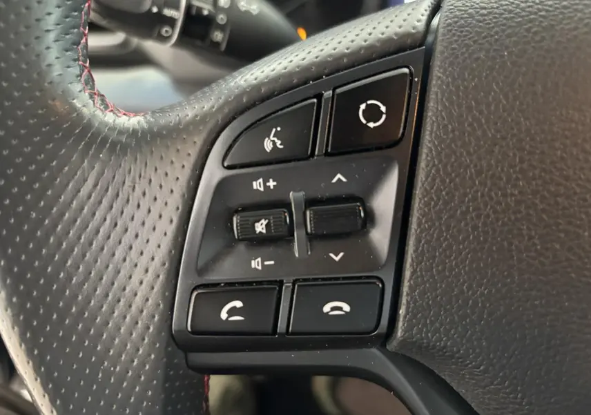 Gros plan sur les commandes gauche du volant cuir noir perforé avec surpiqûres rouges du Hyundai Tucson N Line 2020.