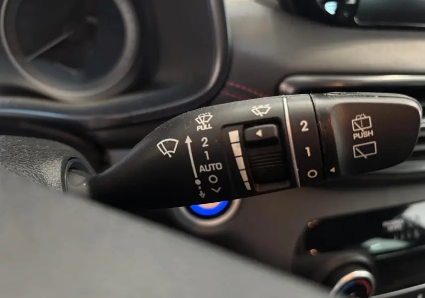 Gros plan sur la commande des essuie-glaces du Hyundai Tucson noir, avec détails des symboles blancs sur levier noir.