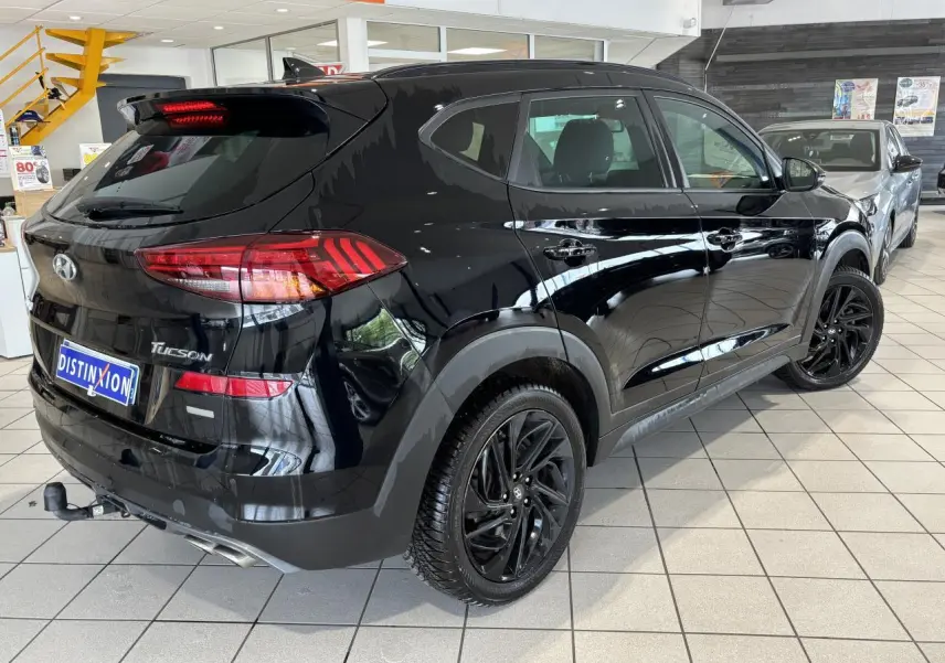 Vue 3/4 arrière droite du Hyundai Tucson noir métallisé avec jantes alliage noires et attelage en concession.