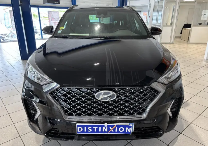 Vue avant d'un Hyundai Tucson noir avec calandre chromée et détails N Line, en intérieur showroom.