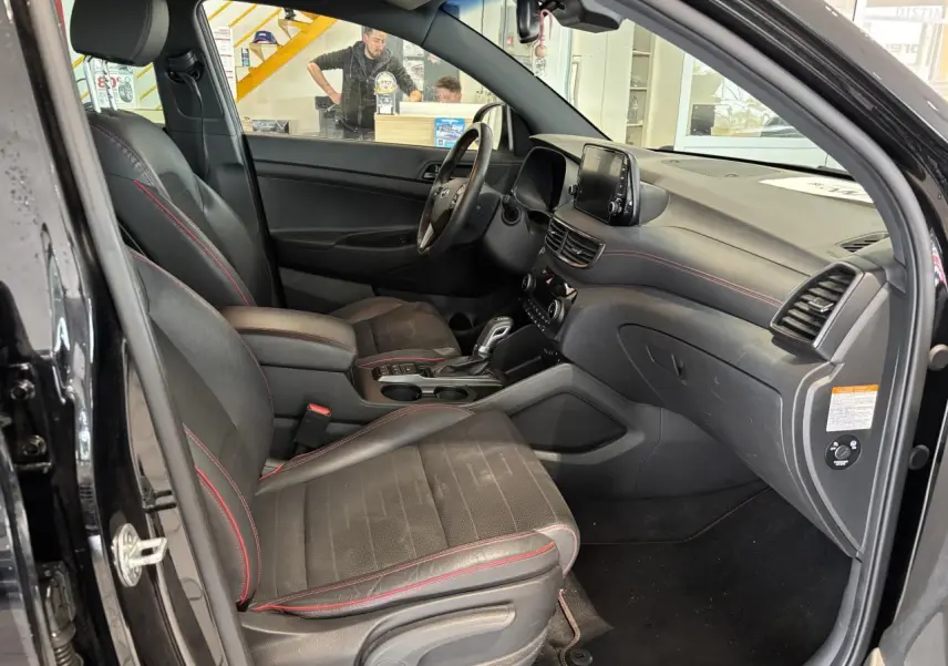 Intérieur noir du Hyundai Tucson 2020 vu côté conducteur, avec surpiqûres rouges et écran tactile central.
