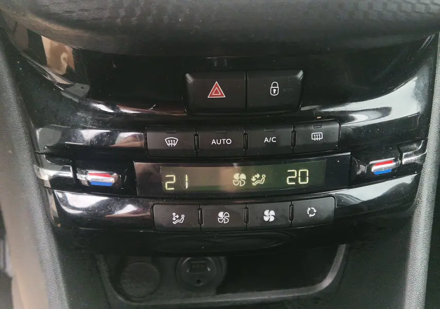 Vue rapprochée de la console centrale noire du Peugeot 208 2018, affichant la climatisation automatique bi-zone.