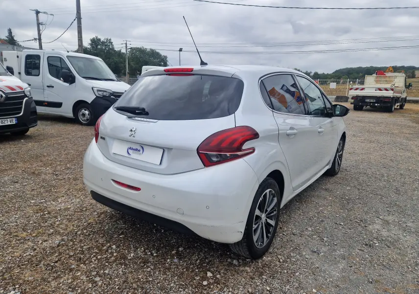 Peugeot 208 blanc nacré vue 3/4 arrière droit, feux arrière distinctifs et jantes alliage bi-ton visibles.