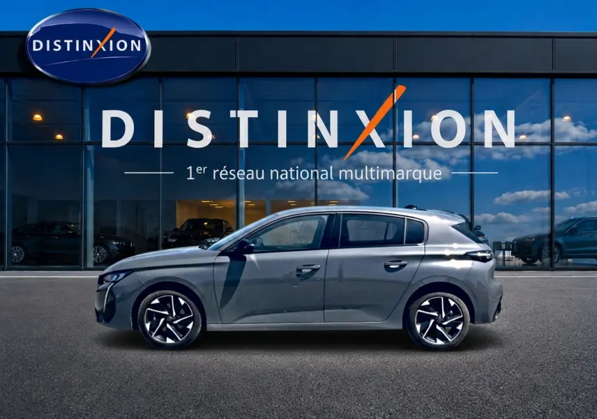 Peugeot 308 gris vue de profil côté gauche, avec jantes alliage et vitres surteintées devant un showroom Distinxion.