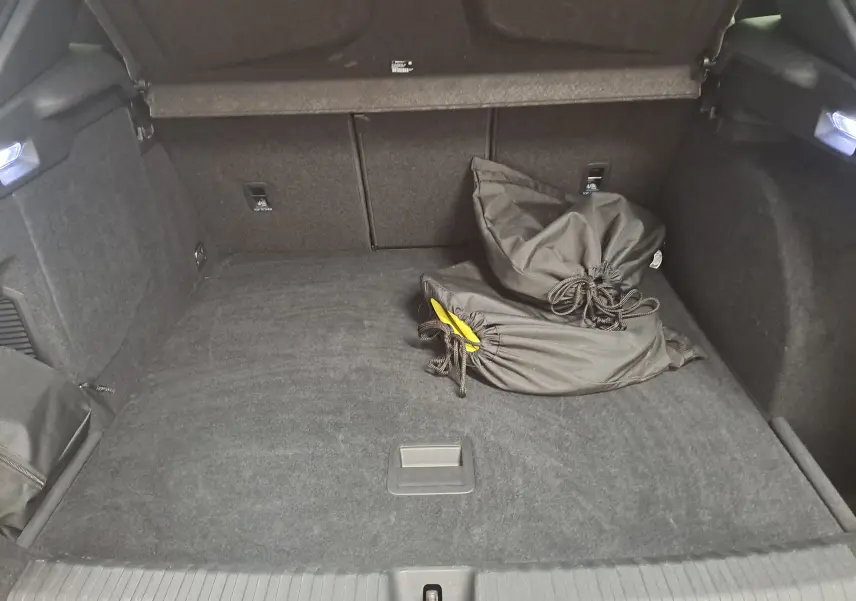 Coffre ouvert vu de l'arrière d'une CUPRA TERRAMAR 1.5 eHybrid bleu cosmos avec sacoches noires à l'intérieur.