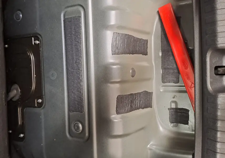 Vue rapprochée du compartiment batterie gris métallique avec un triangle de sécurité rouge dans le coffre d'une CUPRA TERRAMAR hybride.