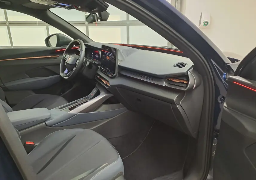 Vue intérieure côté conducteur du CUPRA TERRAMAR bleu cosmos 2025, avec tableau de bord moderne et éclairage d’ambiance rouge.