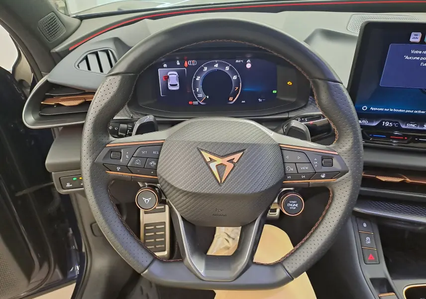Vue intérieure centrée sur le volant perforé noir avec logo CUPRA cuivré et tableau de bord numérique du Terramar 2025.