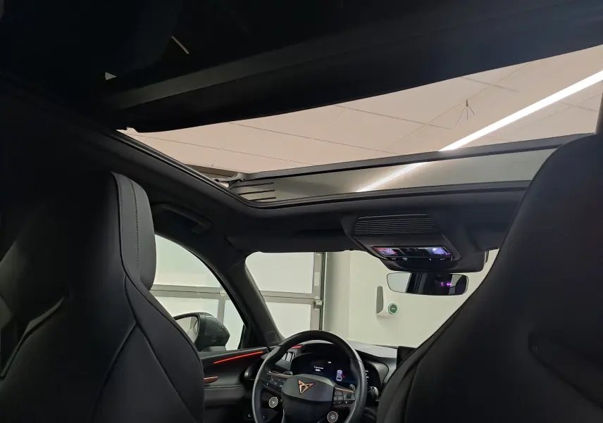 Vue intérieure avant du CUPRA TERRAMAR bleu cosmos, mettant en valeur le toit ouvrant panoramique et le volant multifonction.