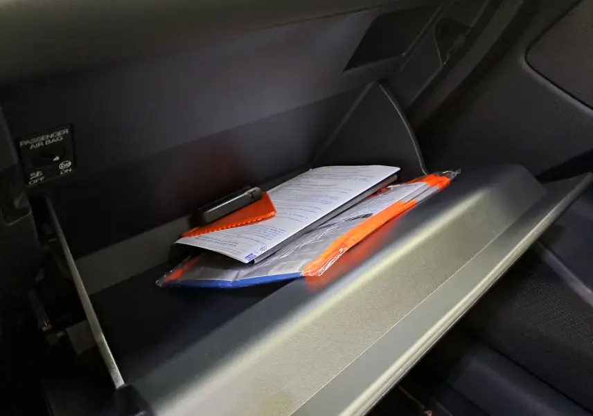 Gros plan sur la boîte à gants ouverte du CUPRA TERRAMAR bleu cosmos avec documents et accessoires visibles à l'intérieur.