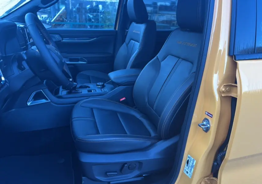 Vue intérieure côté conducteur du Ford Ranger Cyber orange 2026, sièges cuir noirs avec logo Wildtrak brodé.