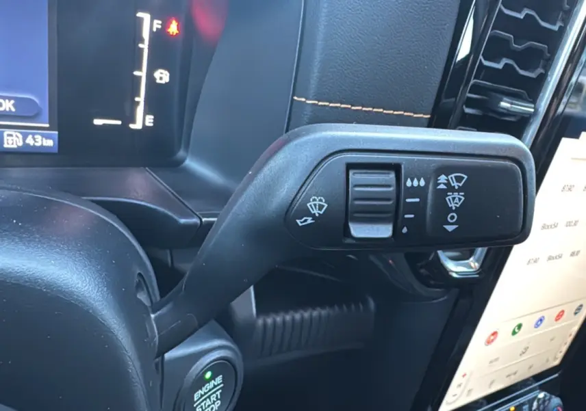 Gros plan sur la commande d’essuie-glace à gauche du volant dans l’habitacle noir du Ford Ranger Cyber Orange 2026.