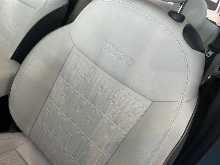 Gros plan sur le siège avant en cuir blanc de la FIAT 500 électrique avec logo 500 embossé sur l'appuie-tête.