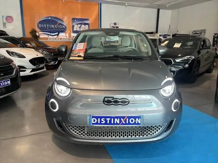 Vue avant d'une FIAT 500 électrique gris minéral métal exposée en showroom avec plaque Distinxion visible