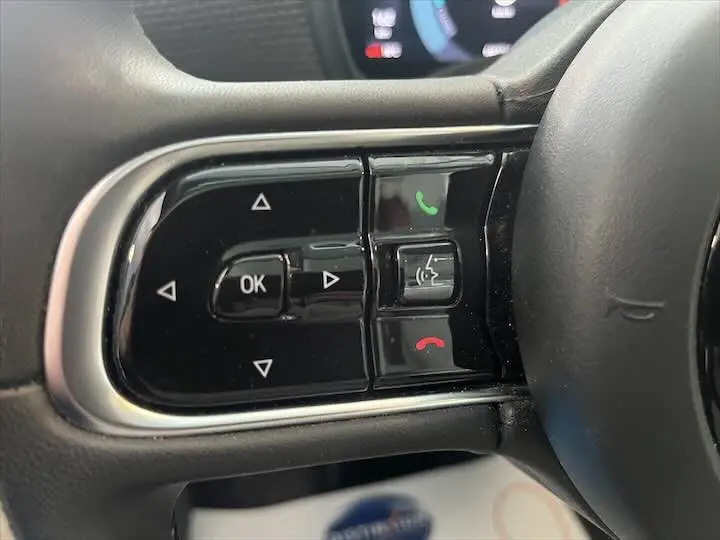 Gros plan sur les commandes multifonctions au volant côté gauche d'une Fiat 500 électrique gris minéral métal.