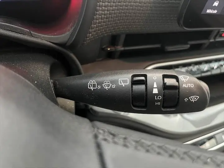 Gros plan sur la commande d’essuie-glace à gauche du volant dans l’habitacle gris foncé de la Fiat 500 électrique.