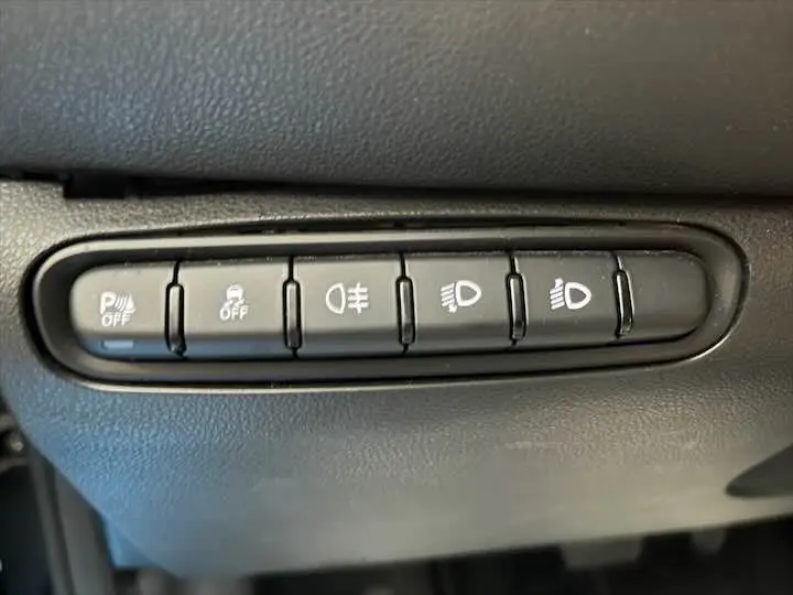 Gros plan sur les boutons de commande des aides à la conduite dans une FIAT 500 électrique gris minéral.