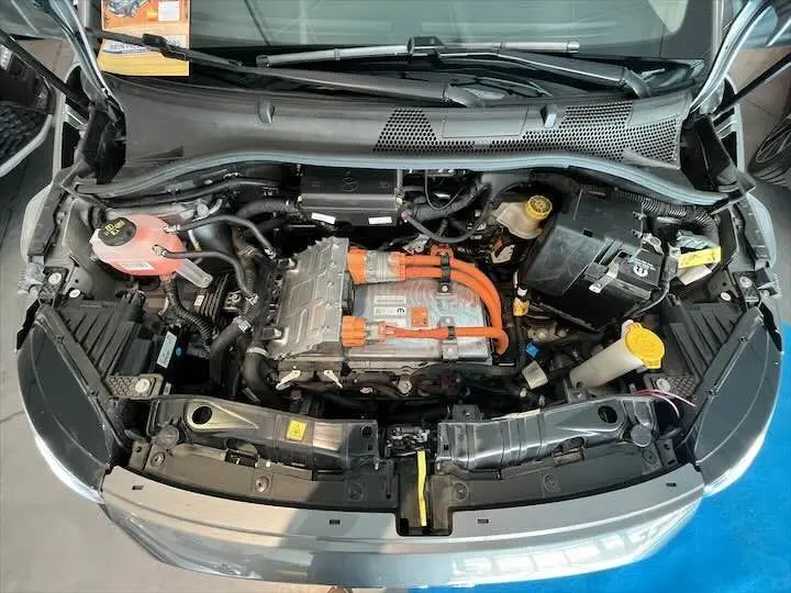 Vue plongeante sur le moteur électrique avec câbles orange du FIAT 500 gris minéral, capot ouvert.