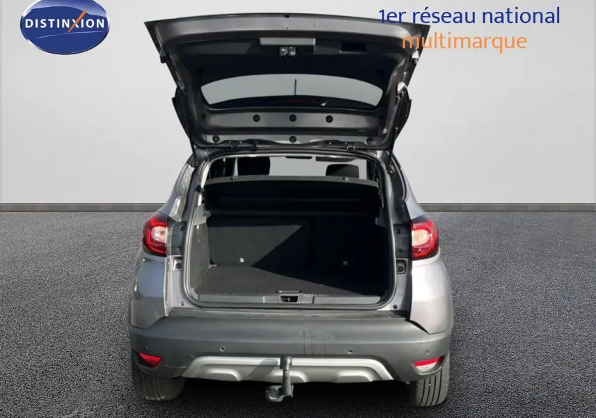 Vue arrière d'un Renault Captur gris 2019 avec coffre ouvert et attelage visible sur sol goudronné.