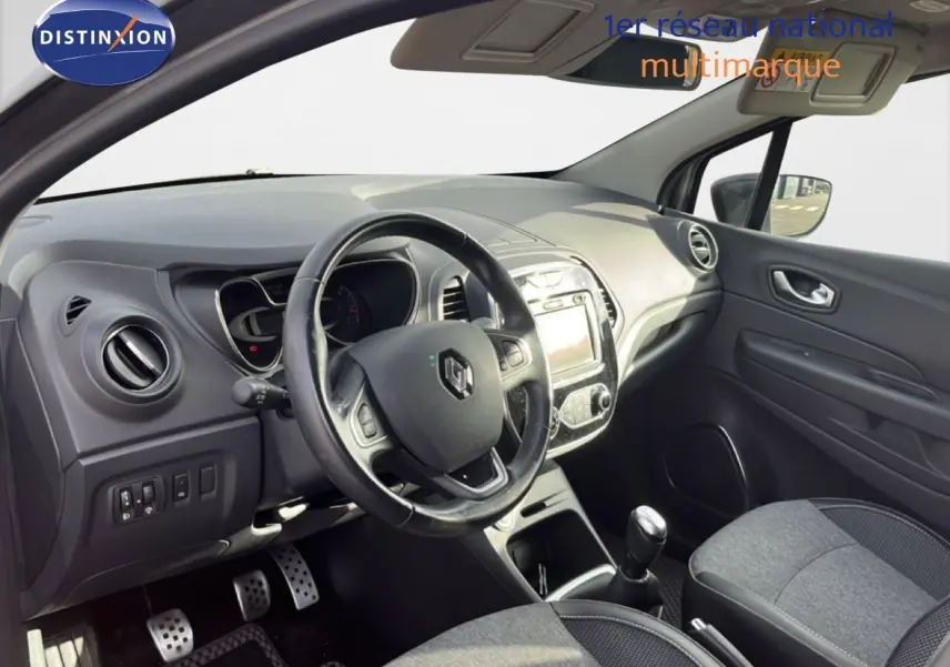 Vue intérieure côté conducteur du Renault Captur gris 2019, montrant le volant, la console centrale et la boîte manuelle.