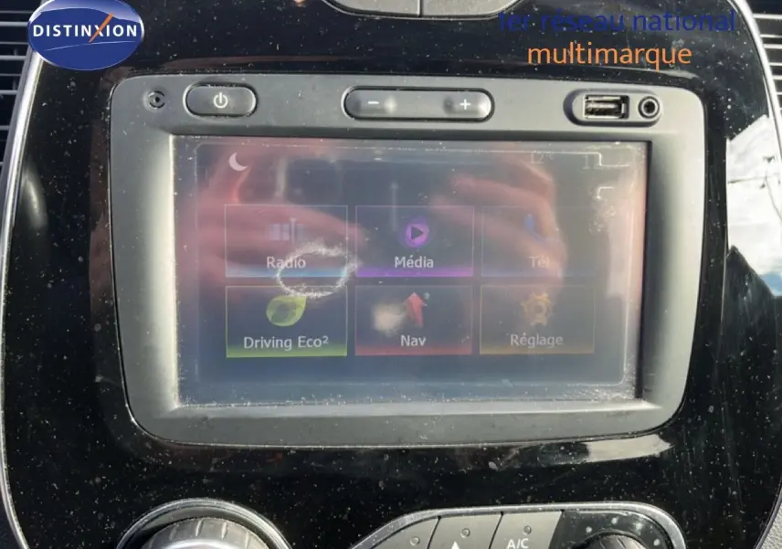 Écran tactile central du tableau de bord du Renault Captur gris, avec commandes multimédia et climatisation visibles.
