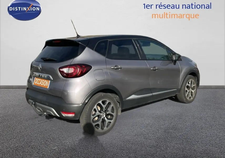 Renault Captur gris vue 3/4 arrière droit, avec jantes alliage et feux arrière distinctifs, stationné sur sol gris.