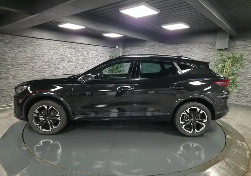 Profil côté gauche du CUPRA Formentor noir avec jantes alliage 18'' usinées dans un showroom intérieur.