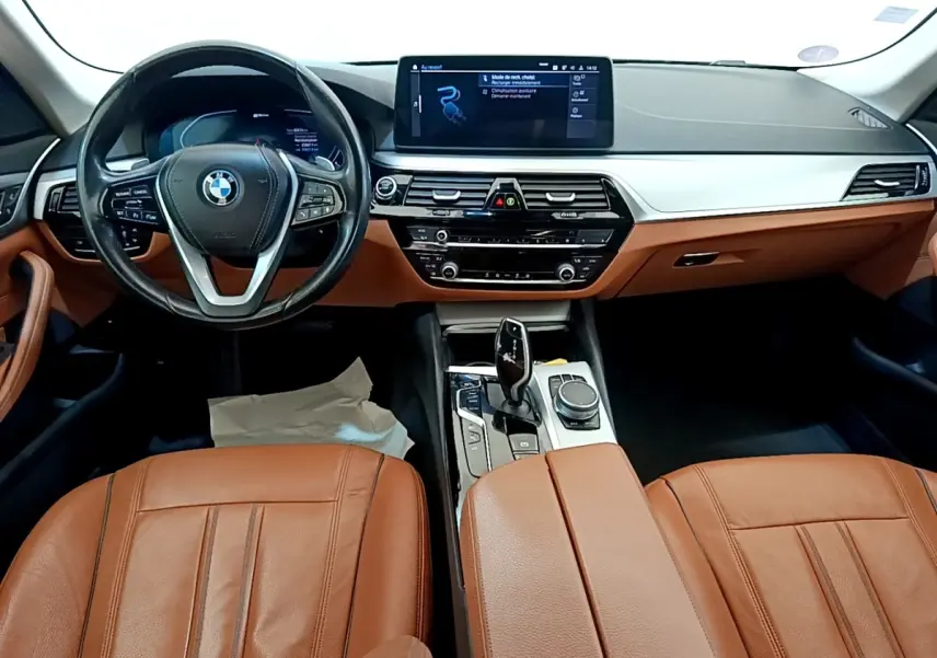 Vue intérieure avant de la BMW Série 5 Touring 530e 2022 avec sièges cuir marron et tableau de bord moderne noir et argent.