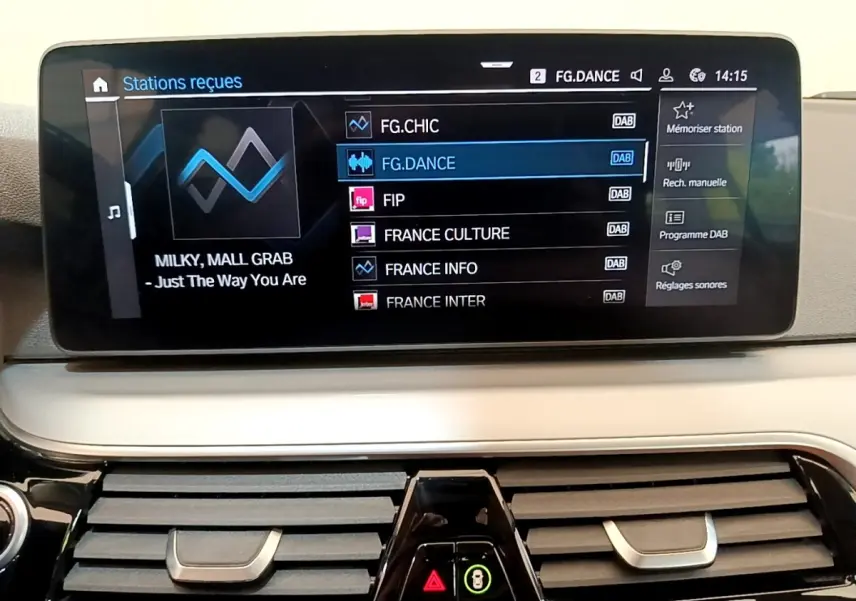 Écran tactile central affichant les stations radio dans l’habitacle d’une BMW Série 5 Touring gris clair, vue de face.