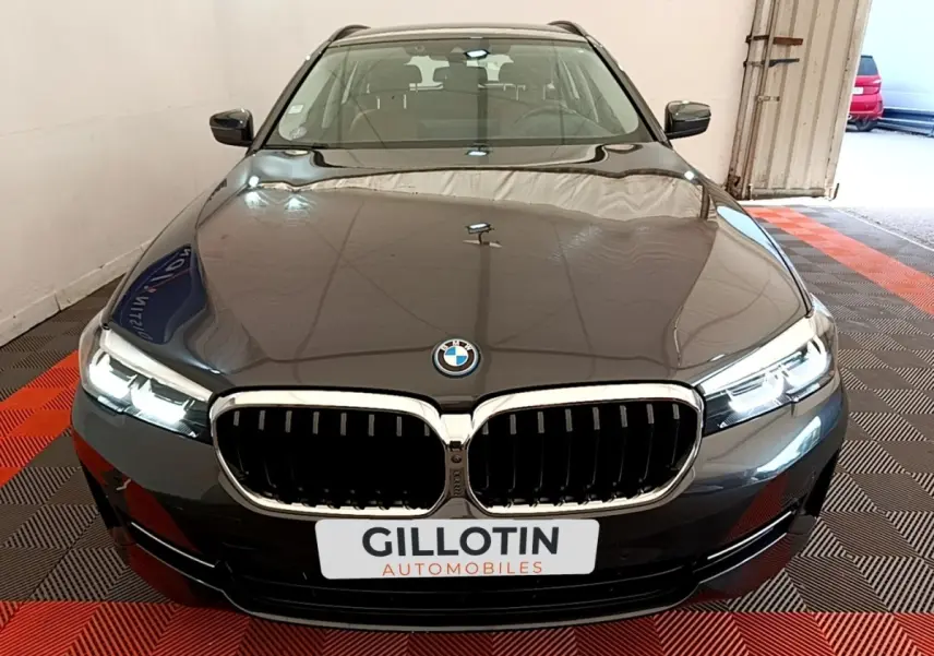 Vue frontale d'une BMW Série 5 Touring 530e gris clair avec calandre chromée et phares LED allumés.