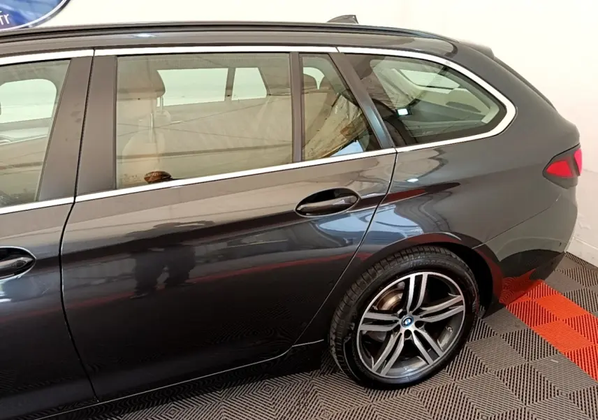 Vue latérale côté droit sur l'arrière d'une BMW Série 5 Touring 530e gris clair avec jante alliage distinctive.