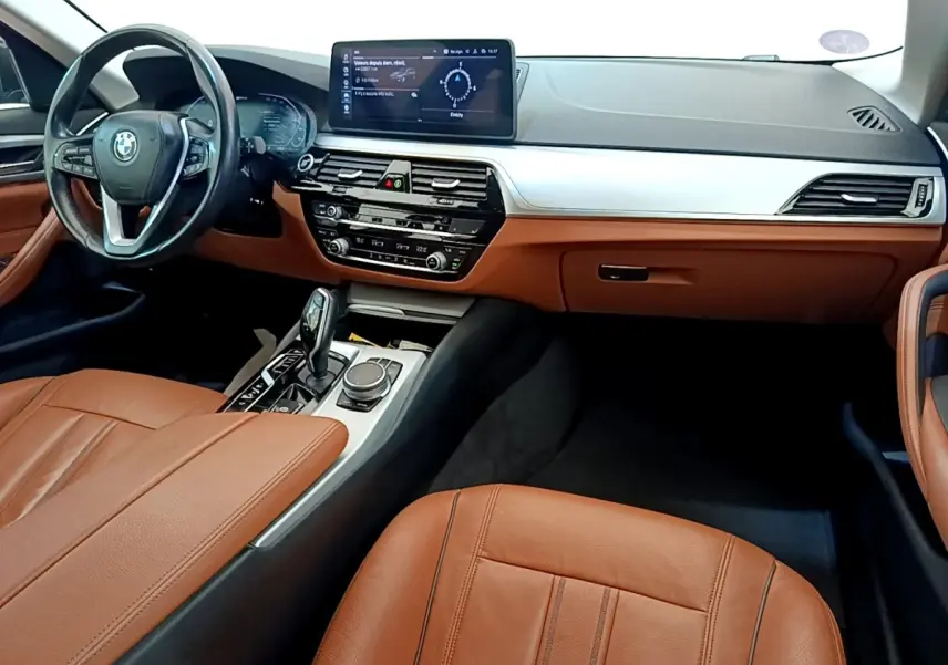 Intérieur BMW Série 5 Touring 530e 2022, vue cockpit côté conducteur, cuir marron et tableau de bord moderne gris clair.