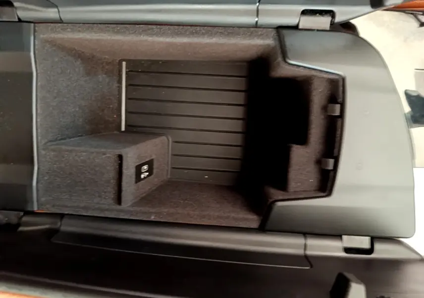 Vue intérieure en plongée du compartiment de rangement central noir d'une BMW Série 5 Touring 530e gris clair de 2022.