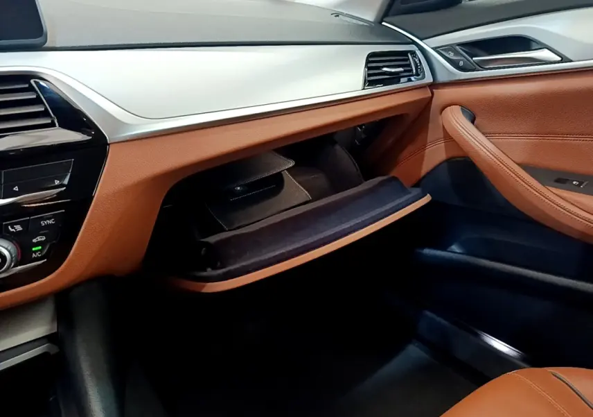 Intérieur avant droit de BMW Série 5 Touring 530e 2022 avec tableau de bord beige et garnitures cuir marron ouvert.