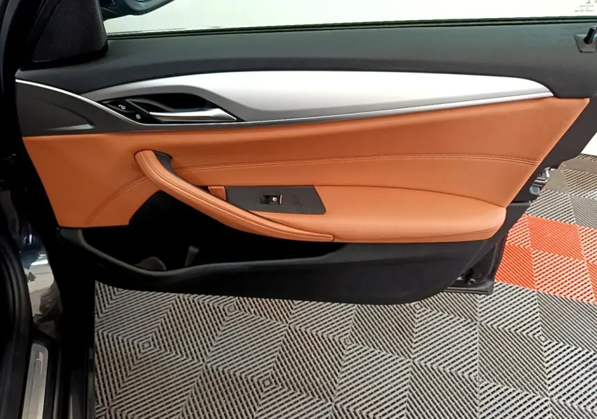 Vue côté gauche de la porte intérieure cuir marron clair et garnitures noires d'une BMW Série 5 Touring 530e 2022.