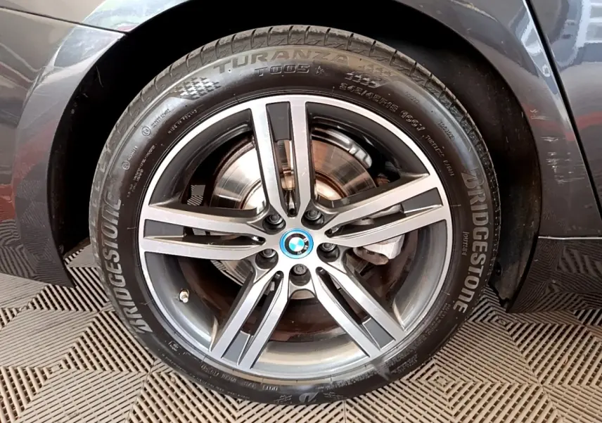Gros plan sur la roue avant droite grise d'une BMW Série 5 Touring 530e avec jante alliage et logo BMW central.