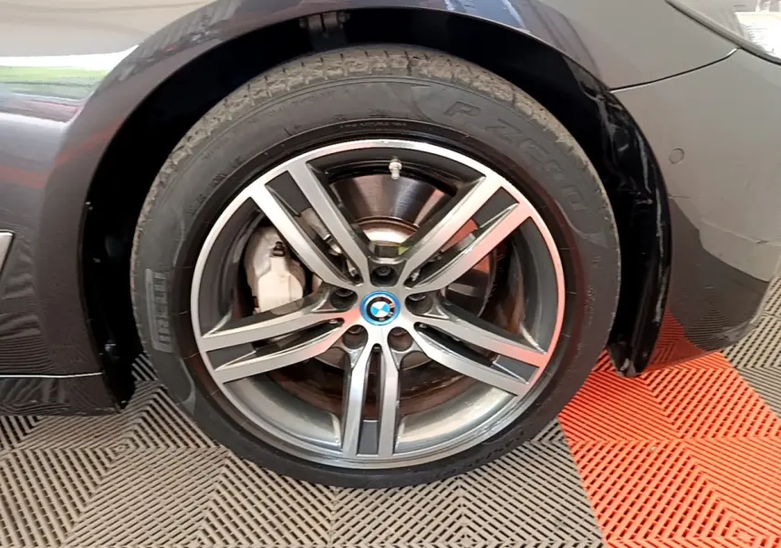 Gros plan sur la roue avant droite gris clair d’une BMW Série 5 Touring 530e avec jante alliage à cinq branches doubles.