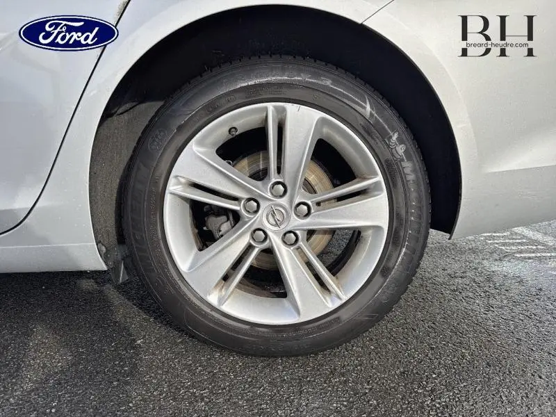 Gros plan sur la roue arrière droite de l'Opel Insignia Sports Tourer gris minéral métallisé avec jante alu à 5 branches doubles.
