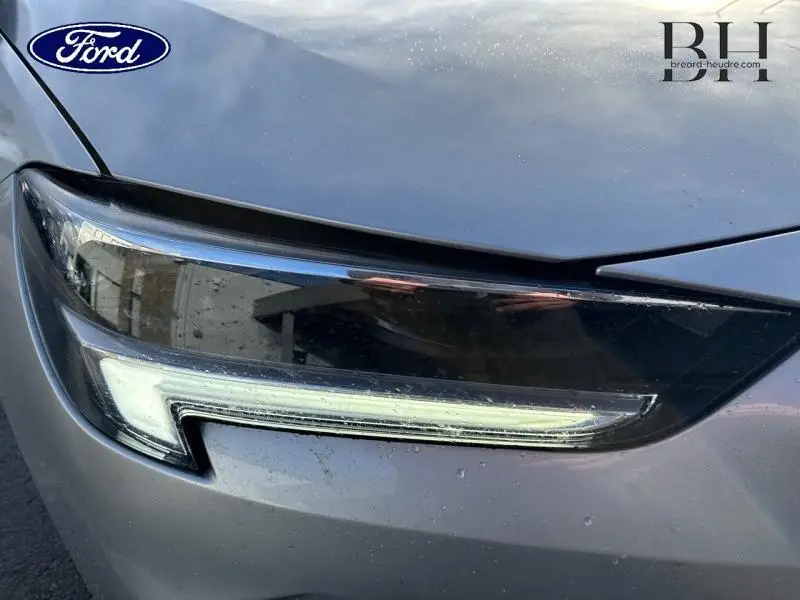 Gros plan sur le phare avant droit gris minéral métallisé de l’Opel Insignia Sports Tourer 2022.