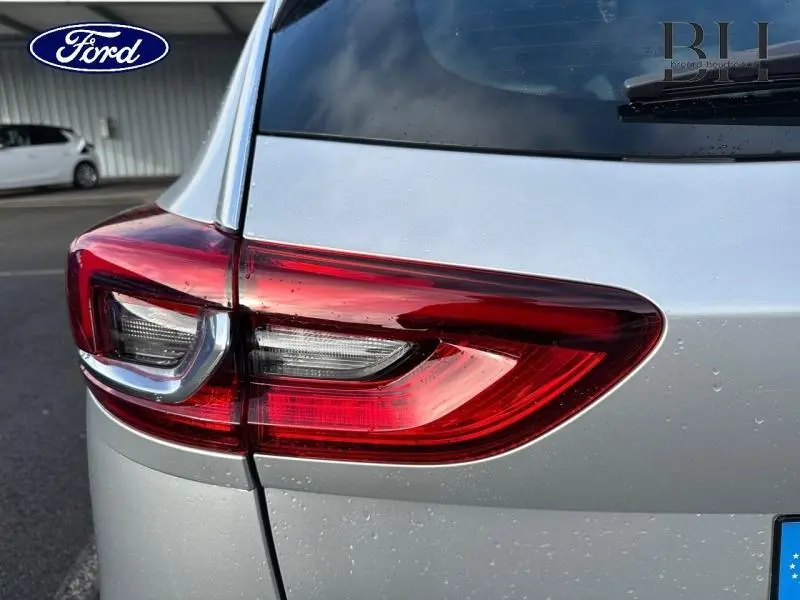Gros plan sur le feu arrière droit d'une Opel Insignia Sports Tourer gris minéral métallisé, avec gouttes d'eau visibles.