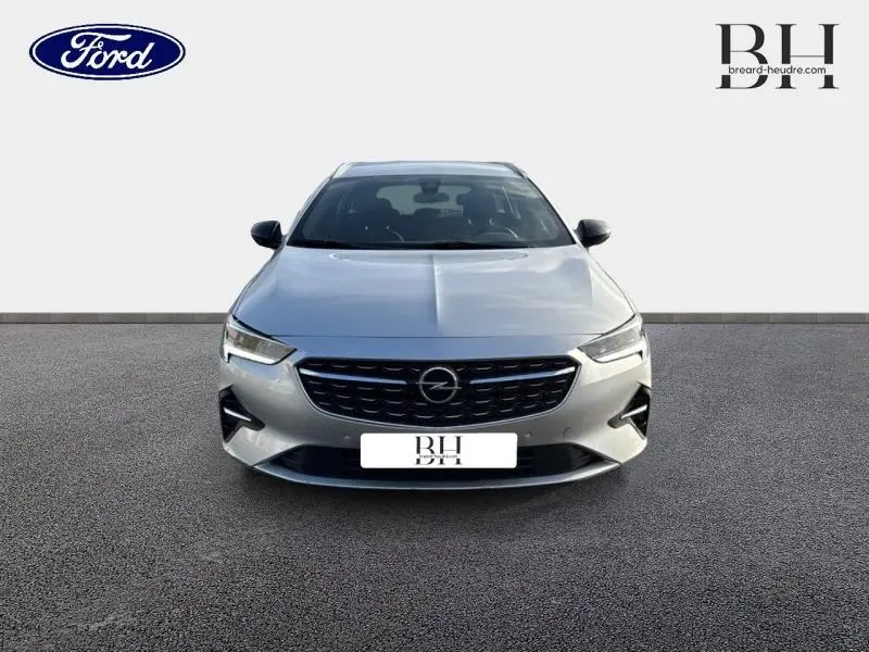 Vue avant d'une Opel Insignia Sports Tourer gris minéral métallisé avec calandre noire et phares LED allumés.