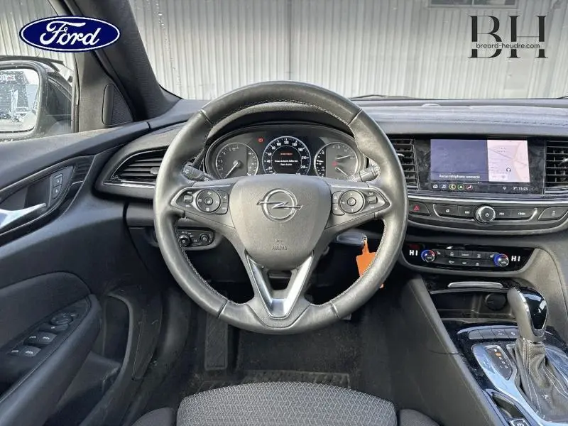 Vue intérieure centrée sur le volant cuir multifonction d'une Opel Insignia Sports Tourer 2022, tableau de bord et écran tactile visibles.