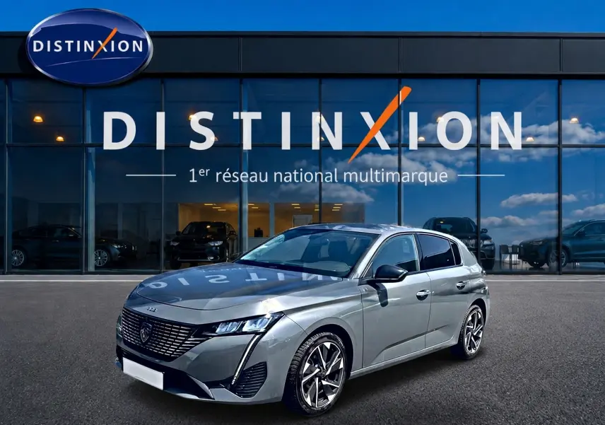 Peugeot 308 gris vue 3/4 avant droit, avec jantes alliage et calandre distinctive, devant showroom Distinxion.