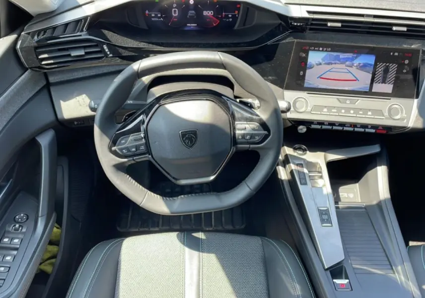 Vue intérieure frontale du poste de conduite gris du Peugeot 308 1.5 BlueHDi avec écran tactile affichant la caméra de recul.
