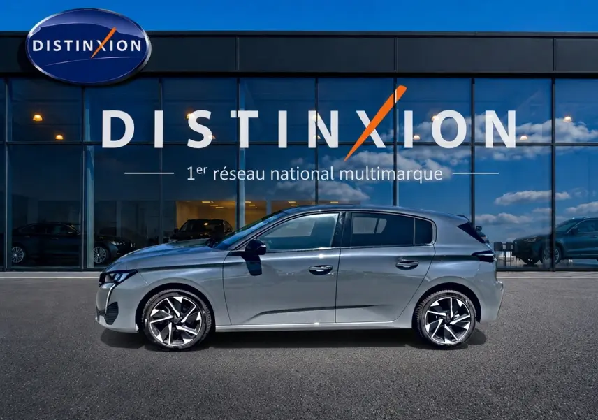 Profil droit d'une Peugeot 308 gris métallisé 2025 avec jantes alliage modernes, devant une vitrine Distinxion.